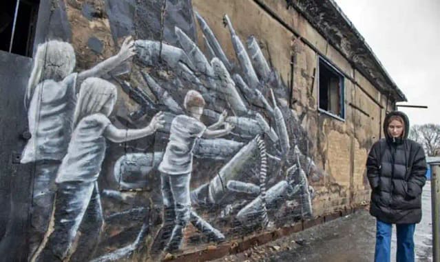 Alemana paseando ante una pintada anti belicista