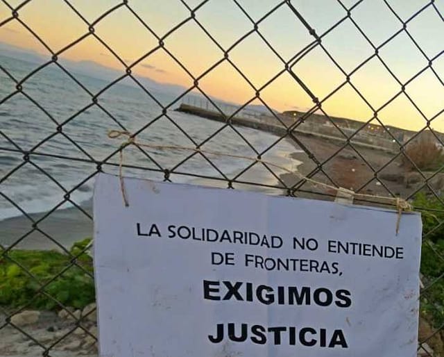 Foto de la valla de Melilla y cartel reivindicativo